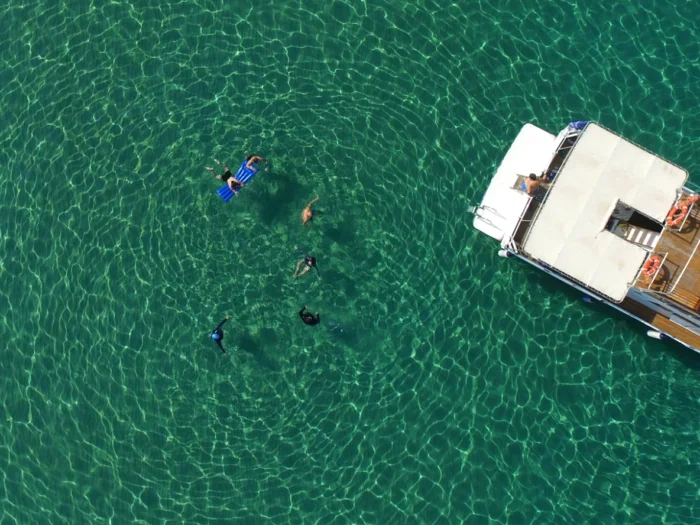 Boat excursion in Alghero with guests snorkeling in the crystal-clear waters of the Coral Riviera.