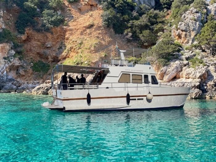 White boat during a boat excursion in Alghero near a cliff with crystal-clear water.