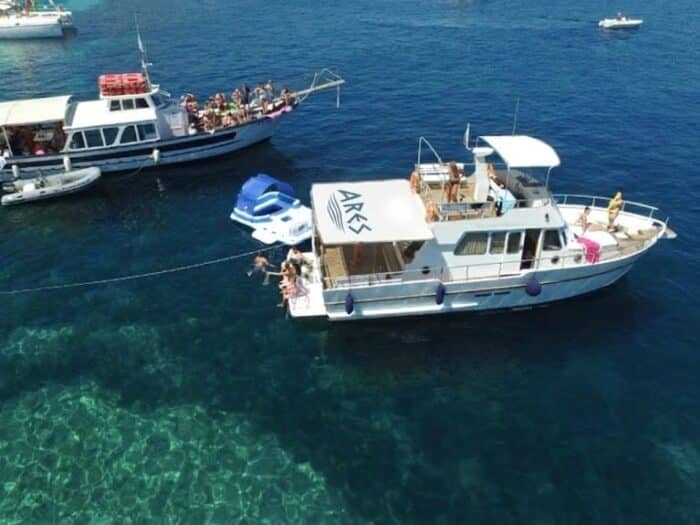 Group of tourists during a boat excursion in Alghero on Ares vessels in crystalline waters.