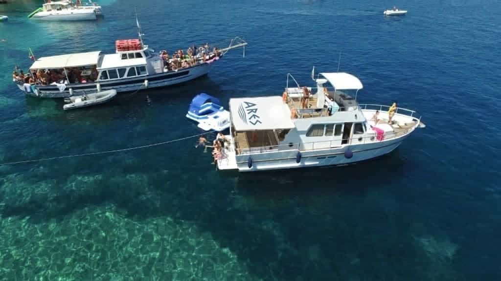 Group of tourists during a boat excursion in Alghero on Ares vessels in crystalline waters.