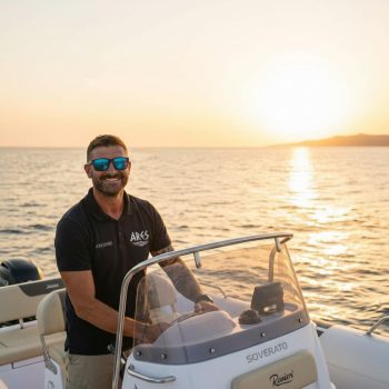 A professional Ares Turismo skipper at the helm of a Ranieri Soverato boat during a private sunset excursion in Alghero